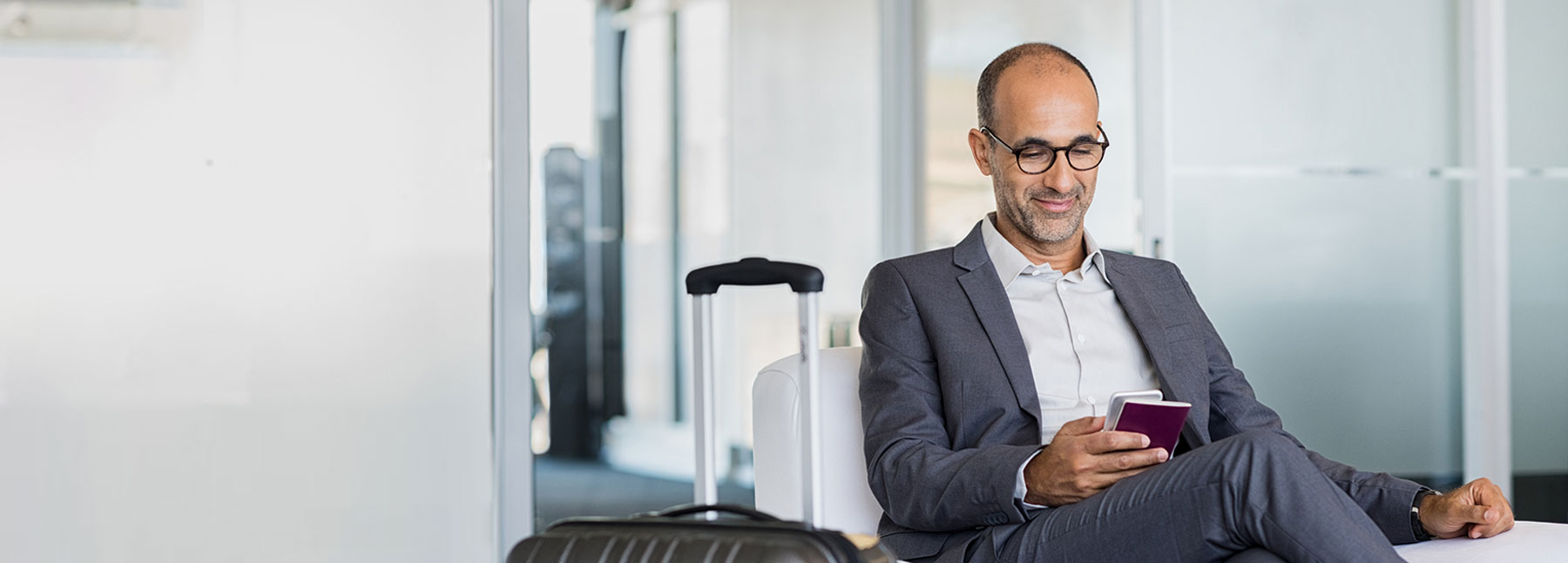 uomo di mezza età calvo all'aeroporto che guarda il suo telefono con un sorriso