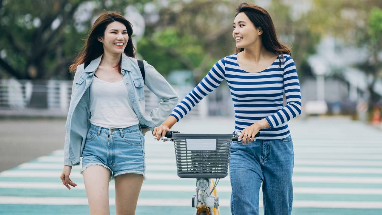 Two women on a street, enjoying a leisurely stroll together.