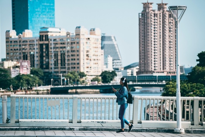 A woman strolling on a bridge over a serene river, enjoying the scenic view and the tranquility of nature.