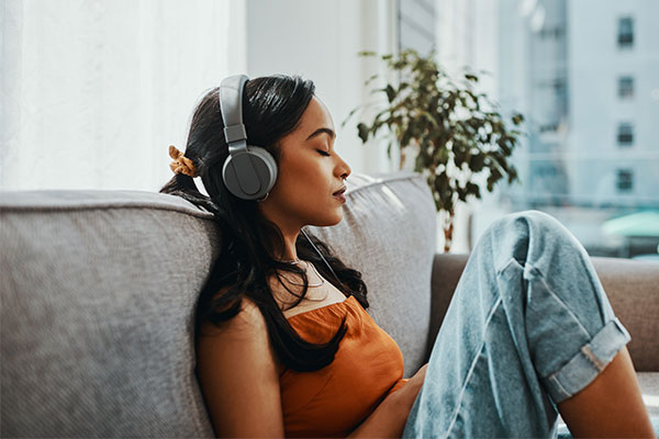 Donna che si rilassa ascoltando la musica sulle cuffie con gli occhi chiusi.